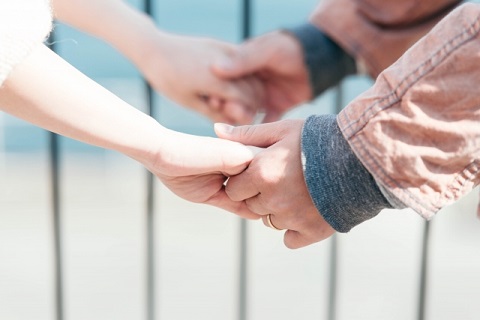 向き合って両手を繋ぐカップルの手